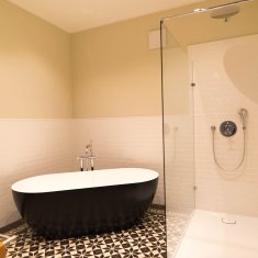 Blick ins Badezimmer mit freistehender Badewanne und Regendusche
